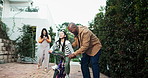 Dad, girl and learning with bike in garden, happy or support with mom recording video for memory at home. People, bicycle and father for smile, mother and daughter with interracial family in backyard