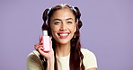 Face, studio and happy woman with cosmetics bottle, facial cleanser or moisturizer. Portrait, skincare product and model with container for toner, dermatology or beauty on purple background space