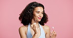 Thinking, woman and application in studio with lip gloss, natural cosmetic and product for trendy makeup. Smile, confident and female person with plumping oil, hydration or beauty on pink background.
