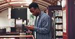 Black man, student and phone for texting in library, scroll and check announcement for exam results. African person, smartphone and mobile app for contact, education or research project at university