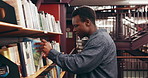 Choosing, books and black man in library at university for research, learning or knowledge. Education, college and African male student with decision on academic information by shelf on campus.