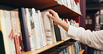 Choosing, books and hands of woman in library at university for research, learning or knowledge. Education, college and female student with decision on academic information by shelf on campus.