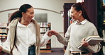 Woman, university student and friends at library with fist bump, greeting and happy at academy. Person, reunion and hello with books, education and smile for learning with scholarship at college