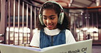 Happy, child and reading book with headphones, library and learning with fiction, knowledge or info. Girl, smile and growth with literature, education and kid with noise canceling tech in school