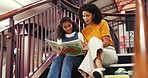 Book, library and mother reading with child for bonding, connection or development together. Happy, education and mom with girl kid for enjoying story on stairs for knowledge and literature learning.