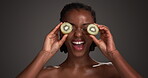 Kiwi, beauty and face of black woman in studio for vitamin c, skincare and natural cosmetics. Exfoliating enzyme, facial glow and dermatology with person and fruit on dark background for antioxidant