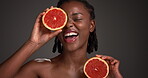Grapefruit, skincare and smile with face of black woman in studio for vitamin c, beauty and natural cosmetics. Exfoliating enzyme, facial glow and dermatology with person and fruit on dark background