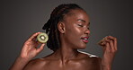 Kiwi, beauty and smell with face of black woman in studio for skincare, vitamin c and organic glow. Natural dermatology, aesthetic and cosmetics with person and fruit n dark background for detox