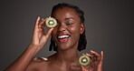 Kiwi, skincare and face of black woman in studio for vitamin c, beauty and natural cosmetics. Exfoliating enzyme, facial glow and dermatology with person and fruit on dark background for antioxidant