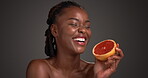Skincare, face or woman in studio with grapefruit, antioxidant or benefit in facial glow. Dermatology, vitamin C or black person on gray background with fruit, collagen or UV protection from citrus.
