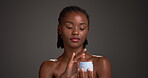 Body, skincare and black woman with lotion in studio, hydration and moisturize benefits in cream Apply, natural and person with wellness product for skin glow, self care and space on gray background.