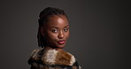 Face, black woman and pride with luxury skincare in studio for cosmetics, dermatology and glamour. Female person, beauty and fur coat for aesthetic, healthy skin and natural shine on dark background