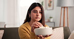Woman, eating or watching tv in house with popcorn for comedy show, film series or relax on weekend. Laughing, female person or snack in apartment for funny movie, streaming service or entertainment.