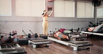 Demonstration, pilates reformer and women with personal trainer in gym for challenge or routine. Exercise, fitness and machine with instructor teaching student group in health club for performance