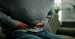 Abdomen, cramps and hands of woman on sofa in living room of home for menstruation or stomach pain. Medical, menstrual cycle and period with person rubbing belly in apartment for discomfort or nausea