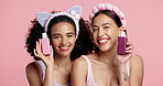 Girl, makeup and bottle with face in studio with friends, smile or results with product on pink background. Women, model and happy together for portrait, beauty or confidence with cosmetics in Mexico