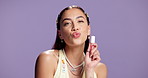 Woman, kiss or face in studio with lip gloss, make up or product testing in mockup space. Happy, person or model for beauty with purple background, cosmetic or brand advertisement for trends.