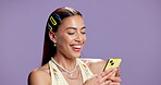 Happy, girl and typing with phone in studio for text message, social media update and reading post. Mockup space, gen z person and smile with smartphone on purple background for status upload or chat