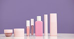 Makeup, product and bottles in studio for skincare, cosmetics and beauty for advertising. Mockup space, cosmetology and container for salon aesthetic, dermatology and selection on purple background