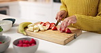 Hands, chopping board and fruit in kitchen, home and meal prep with strawberry, banana and knife. Person, chef and cutting organic ingredients for diet, nutrition or weight loss for wellness at house