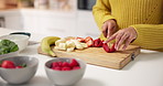 Hands, chopping board and strawberry in kitchen, home and meal prep with fruit, banana and knife. Person, chef and cutting organic ingredients for diet, nutrition or weight loss for wellness at house