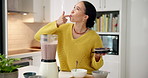 Woman, blender and taste with finger, smoothie and test flavor with healthy drink for nutrition in home. Person, diet and machine for milkshake, weight loss or wellness in kitchen at apartment