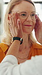Optometrist, mature woman and hands with glasses for eye care, smile or assessment for choice at store. People, ophthalmology and customer experience with spectacles, fitting and prescription at shop