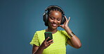 Black woman, headphones and dance with phone in studio for streaming, listening to music and audio. Person, energy and mockup space with mobile, moving rhythm and online playlist on blue background