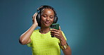 Black woman, headphones and dancing with phone in studio for streaming, listening to music and audio. Person, energy and mockup space with mobile, moving rhythm and online playlist on blue background