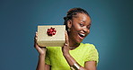 Black woman, excited face and gift in studio with smile, shake or guess for birthday on blue background. African girl, box and present with mockup space, happy or celebration with portrait in Nigeria