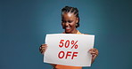 Black woman, face and poster with discount in studio for advertising deal on a blue background. Portrait, female person or happy with paper sign for marketing sale, half price off or saving on space