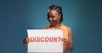 Black woman, face and poster with discount for advertising deal on a blue studio background. Portrait, female person or happy with paper sign for marketing sale, half price off or bargain on space