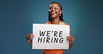 Black woman, face and post for hiring in studio with smile, pride or recruitment drive on blue background. Person, agent or human resources manager with sign for onboarding with mockup space in Kenya