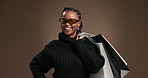 Black woman, sunglasses and shopping bag in studio for smile, retail therapy and fashion sale on background. African girl, happy and face with customer experience, discount deal or pride in Kenya