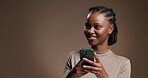 Laughing, phone and thinking with black woman on studio space for contact or social media. App, idea and typing text message with funny African person on brown background for mobile communication