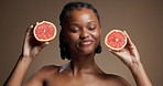 Grapefruit, black woman and smile in studio for skincare, vitamin c and natural beauty for wellness. Organic, happy person and dermatology with citrus fruit, skin glow and space on brown background.