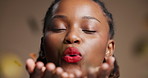 Black woman, confetti and makeup with celebration in studio for new year on a brown background. Female person, face or African model blowing glitter with smile for party, event or festive memory