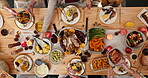Above, hands and food with friends at dining room table together for thanksgiving celebration. Dish, meal and passing with group of people in home for event, sharing dinner or social gathering