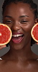 Face, grapefruit and skincare with excited black woman in studio for detox or health benefits. Beauty, citrus and vitamin c with happy African model on gray background for diet, nutrition or wellness