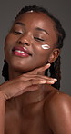 Cream, skincare and black woman with beauty, smile and dermatology on grey studio background. African person, glow and lotion with healthy skin, cosmetics and aesthetic with grooming and treatment