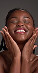 Skincare, black woman and smile with makeup in studio, natural beauty or smooth texture in spa treatment. Facial glow, happy person or dermatology for shine, self care and wellness on gray background