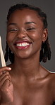 Black woman, face and toothbrush with makeup in studio for dental care on a gray background. Portrait, female person or African model with smile or bamboo stick for oral, mouth or gum care routine