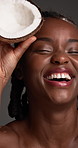 Black woman, skincare and face with coconut in studio, laugh and sustainable cosmetics on background. African person, organic fruit and dermatology with laugh, product and beauty benefits in Kenya