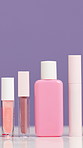 Empty, bottle and cosmetics in studio for skincare, beauty and product review on purple background. Space, salon and selection of container for shine, wellness or aesthetic for dermatology campaign