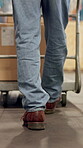 Back, feet and walking with person in warehouse for inventory, stock or storage management. Boxes, legs and trolley with employee in factory or plant for delivery, logistics or supply chain career
