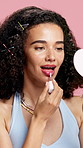 Woman, mirror and lipgloss for beauty in studio for lip hydration, smooth texture and treatment. Female person, product and cosmetics for change, grooming and shine for aesthetic on pink background