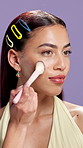 Beauty, makeup and brush with face of woman in studio for shine, foundation application and self care. Blush powder, aesthetic and highlighter glow with person on purple background for cosmetics
