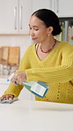 Woman, cleaning and spray kitchen counter in home for hygiene maintenance, sanitation or chores. Housekeeping, cloth and happy person wipe table with bottle for bacteria safety or germ prevention