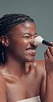 Beauty, laughing and makeup brush with black woman in studio to apply facial foundation. Contouring, blush and funny with happy African model on gray background for application of cosmetic product