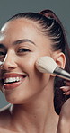 Face, woman and smile with makeup brush in studio with beauty, foundation and aesthetic. Portrait, female person and cosmetic tools for makeover, facial powder and natural shine on gray background